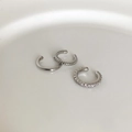Dettaglio di tre ear cuff in argento con design liscio, a spirale e con zirconi bianchi - Ear Cuff con Zirconi (Colore Argento)