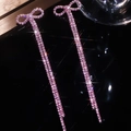 Dettaglio di orecchini a fiocco con cristalli rosa e lunghe nappe su sfondo nero - Combinazione fiocco / Rosa(DTE1816359P)