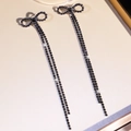 Dettaglio macro di orecchini a fiocco con strass neri e lunghe catene pendenti a frangia - Combinazione fiocco / Nero(DTE1816359BK)