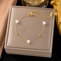 Elegant gold titanium bracelet featuring three white pearls and beads on a grey jewelry box - E121 Pearl Gold Bead Bracelet Gold