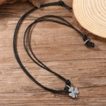 Dettaglio del ciondolo a quadrifoglio vintage su cordino in pelle su base in legno - Stile Trifoglio / Nero