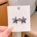 Pair of vintage silver star stud earrings on white display card held by hand - Gun Black Star Waist Buckle