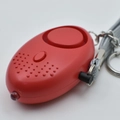 Red personal safety alarm with LED light, activation pin, and gray braided lanyard keychain - Red