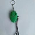 Green personal security alarm for women featuring a metal keychain and a functional LED light - Green