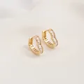 Detailed view of heart-shaped gold earrings set with rectangular cubic zirconia stones - White Zirconia Heart Huggie (15x15mm)
