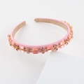 Detailed view of pink crystal headband with gold metal settings and satin finish - Pink