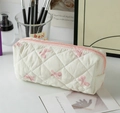 Detail of quilted cosmetic bag with pink bow prints and zipper closure in cozy setting - White with Pink Bow