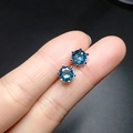 Macro shot of blue sapphire stud earrings in six-prong silver setting on fingers - Blue Rhinestone