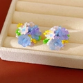 Close-up of colorful resin flower beaded clip-on earrings in a beige jewelry box. - Blue-Purple