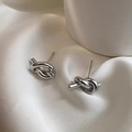 Pendientes de nudo plateados minimalistas con acabado pulido sobre fondo seda blanca - Estilo Anudado / Color Acero (G191)
