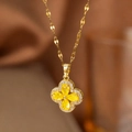 Détail d'un collier trèfle doré avec gemmes jaunes en forme de cœur et strass brillants - Trèfle Jaune (Chaîne Dorée)