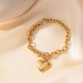 Pulsera de amuleto de corazón dorado con cierre de barra sobre fondo de seda beige - Cierre de Palanca Gran Corazón (E2181) / Dorado