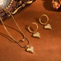 Gedetailleerd beeld van een vergulde hartjesketting en bijpassende oorringen set. - Puntig Hart Halsketting Oorbellen / Goud