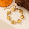 Primer plano de una pulsera con dijes de concha dorada sobre un fondo de madera estético - Pulsera de Conchas Enlazadas (E2125) / Dorado
