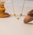 Dettaglio della collana dorata con tre ciondoli a margherita e catena a sfere opaca - Stile Tre Margherite (QYH16)