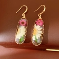 Macro view of handmade resin oval drop earrings featuring real dried daisy flowers - Ear Hooks-Oval / White-Pink