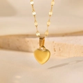 Vue macro du collier pendentif cœur en or brossé mat sur un support en pierre beige - Collier Cœur 3D (QYH691) / Or