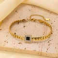 Close-up of gold chain bracelet featuring a black gemstone square charm on stone base - Gold Black Zirconia Bracelet