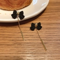 Elegant black bow earrings with long gold chain tassels on a cozy wooden table background. - Black Bow Tassel Style / Silver Needle