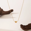 Detailed view of a golden heart pendant necklace on minimalist dark wood and beige background - Tiny Heart Necklace / Gold