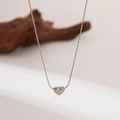 Close-up of a minimalist silver heart pendant on a fine cable chain with polished finish - Tiny Heart Necklace / Steel
