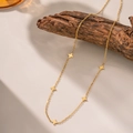 Élégant collier doré avec cinq breloques étoiles à quatre branches sur fond de bois - Collier Trèfle Brillant (H377) / Or