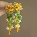Close-up of handmade yellow floral tassel earrings with green beads and white flower charms - Green-Yellow Tassel (925 Sterling Silver Earring Post)