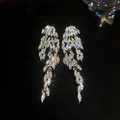 Macro detail of luxury sparkling leaf-shaped silver needle drop earrings with stones - Style 56