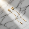Detail of 18K gold clover heart drop earrings on a white marble background with shadows - Heart to Heart (QYG334)