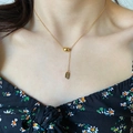 Collar de titanio dorado con colgante Lucky grabado mostrado en el cuello de modelo - Collar Etiqueta Cuadrada Frijol (H317) / Dorado
