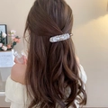 Elegante fermaglio per capelli con perle e conchiglie su capelli marroni mossi - Petalo di Perla Elegante alla Moda
