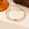 Detail eines 18K vergoldeten Knot-Armreifs mit seidenmattem Finish auf edlem Display - Offener Knoten Stil (QYE105) / Gold