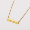 Vista detallada de un collar de barra chapado en oro de 18k con texto grabado festivo - Dorado