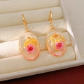 Close-up of elegant resin drop earrings with real dried flowers in a jewelry box - Gold Round Yellow Hook