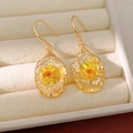 Detail view of oval resin earrings with yellow dried flowers in a beige jewelry box - Oval Teardrop / Ear Hook-Yellow