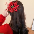 Close-up detail of a vivid red spider lily flower hair clip on long wavy dark hair - Spider Lily Duckbill Clip / Red