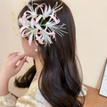Close-up detail of a pink acrylic spider lily hair clip worn on long wavy hair - Spider Lily Duckbill Clip / Pink
