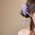 Eleganter lila Blumen-Haarclip mit langer goldener Quaste an der Haaren der Frau - Lila Spinnenlilie Goldkettchen-Stil / Lila
