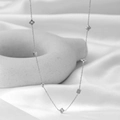Minimalist silver clover and cube charm necklace displayed on elegant white silk fabric - Steel Color Necklace (QYH625)