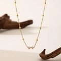 Golden bow bracelet with zircon stones on thin beaded chain over natural wood aesthetic - Zircon Bowknot Necklace (QYH224) / Gold