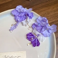 Primer plano de elegantes pendientes de flores de gasa morada con borlas y perlas - Estilo 24 (Poste Plata)