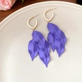 Primer plano de pendientes de borla de pétalos morados con aros dorados en un plato. - Estilo de Pasador de Plata / Púrpura