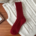 Warme dunkelrote Wollsocken mit Rippstrick-Muster auf einer Strickweste präsentiert - Breit Gerippter Stil