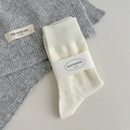 Folded white textured ribbed socks with premium paper band on grey knit background - One Size / White