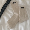 Beige mid-calf knit socks with black woven label detail on textured cream fabric - Oatmeal