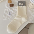 Mittelhohe beige Strickstulpen mit grauem Maus-Label und gerippter Textur für den Alltag - Cremefarben