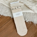 Retro cremefarbene Strickstrümpfe mit Blumenstickerei und gewelltem Rüschenrand im Detail - Creme Welle