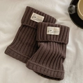 Dark brown ribbed knit leg warmers with a minimalist cloth tag on white bedding - One Size / Coffee