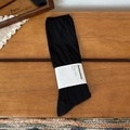 Classic black ribbed knit crew socks with minimalist brand paper wrap on a wood surface - One Size / Black
