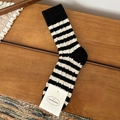 Gemütliche Wollsocken mit klassischen schwarz-weißen Streifen auf warmem Vintage-Holzhintergrund - Schwarz